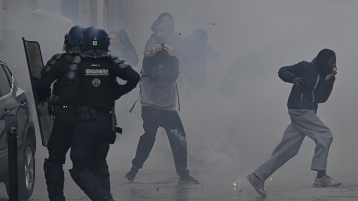 Des manifestants s’enfuient alors que des grenades lacrymogènes sont lancées.