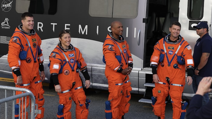 Jeremy Hansen, Christina Koch, Victor Glover et Reid Wiseman, dans leur combinaison d’astronaute, sourient à la foule alors qu’ils répètent une sortie. 