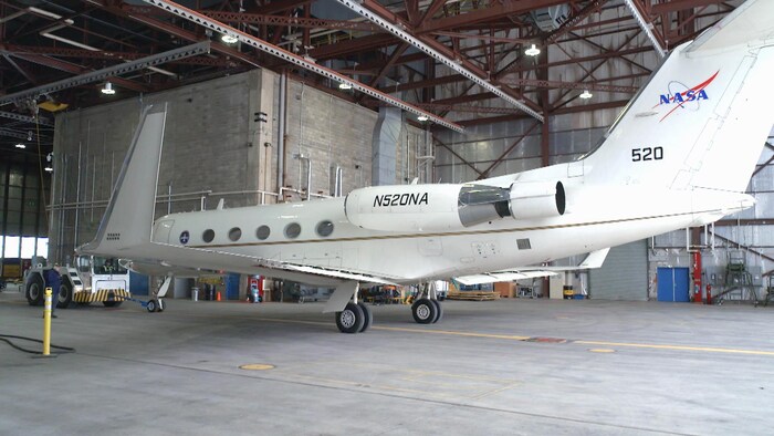 Un avion Gulfstream III blanc décoré du logo de la NASA, dans un hangar.