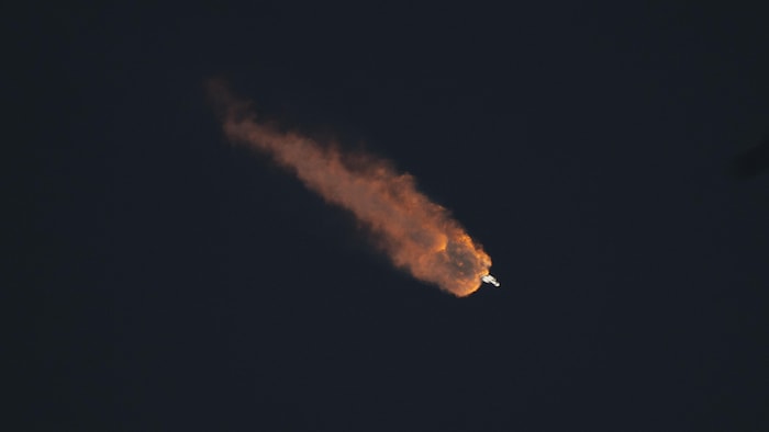 Une fusée en plein vol dans l'espace, avec une traînée de feu derrière elle.