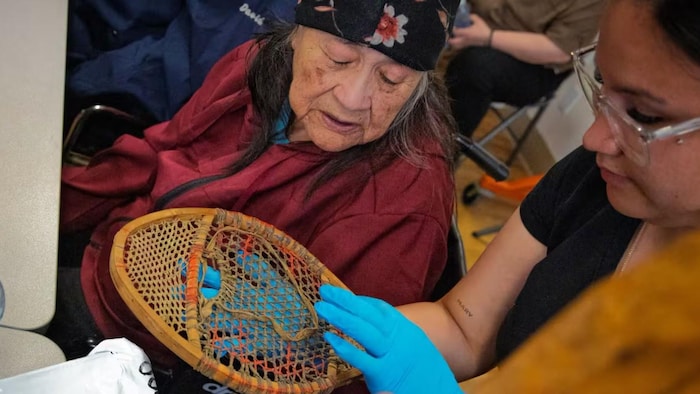 Une aînée observe une ancienne raquette.