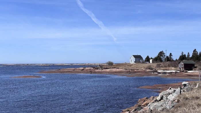 Une maison fait face à la mer par une journée ensoleillée.