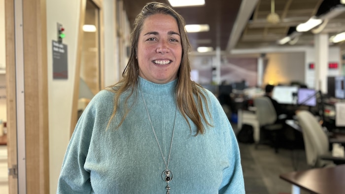 Une femme sourit devant la caméra dans notre studio.
