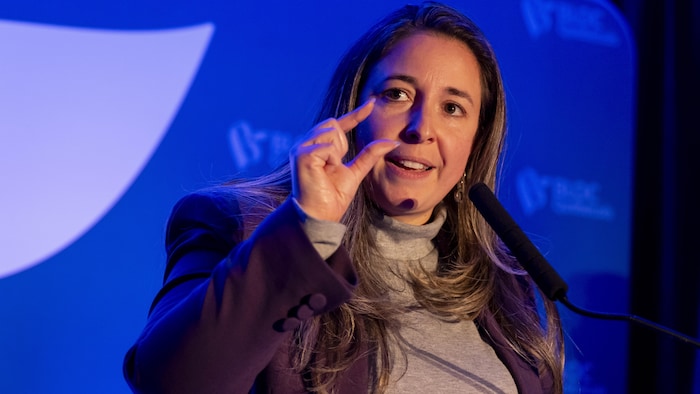 Elle fait un geste de la main droite.