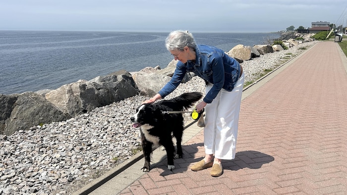 Nathalie St-Onge caresse son chien Goliath près de l'eau.