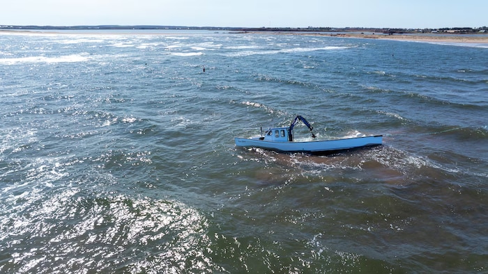 Un bateau de pêche échoué près de la côte et à demi rempli d'eau.