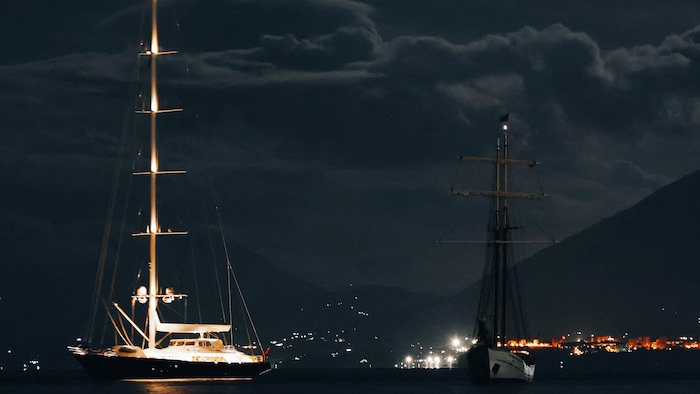 Bayesian supersailing ship illuminated at night.