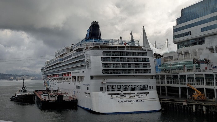 Un immense navire est au quai du port de Vancouver avec en arrière-plan des nuages menaçants.