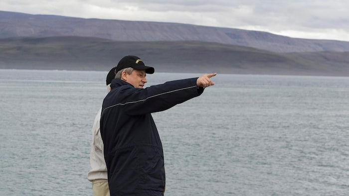 Stephen Harper with another individual pointing to the horizon on the shoreline in Nunavut.