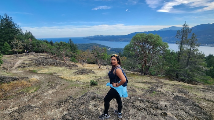 Nawal Lasfar, coordonnatrice à la Communauté francophone accueillante (CFA) de Nanaimo au milieu d'arbres, proche de la mer.