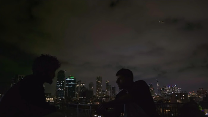 Deux hommes parlent dehors la nuit.