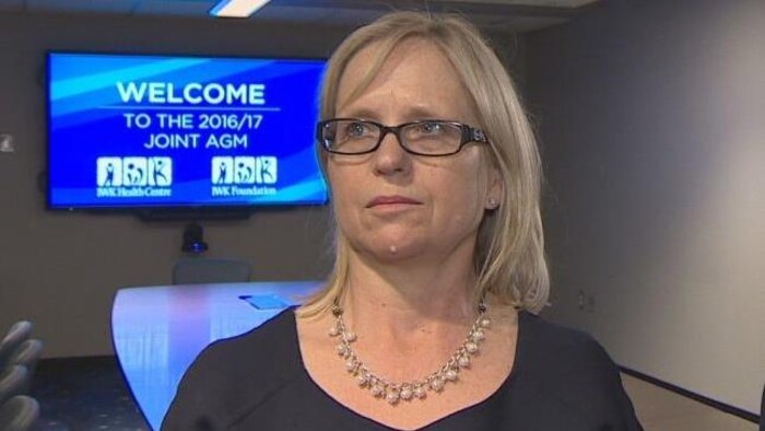 Tracy Kitch pose devant un écran de télévision bleu dans une salle de réunion.