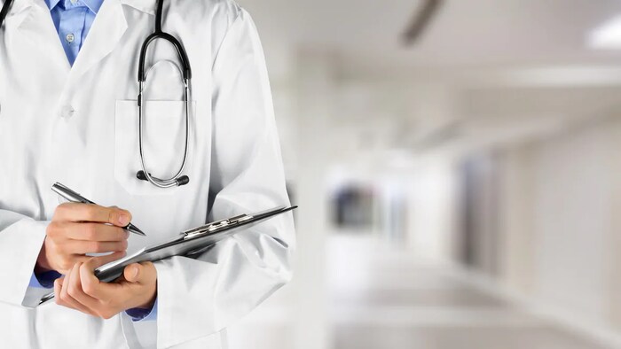 Buste d'une personne portant une blouse blanche, un stéthoscope et tenant un carnet et un stylo dans les mains.