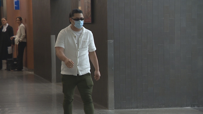 Nedjem Eddine Khirat marche dans les couloirs avec des lunettes fumées et un masque chirurgical.
