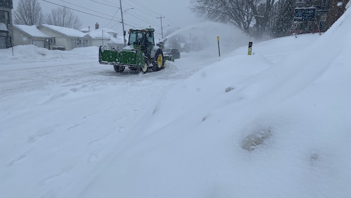 Un camion de déneigement est en train de nettoyer une rue.