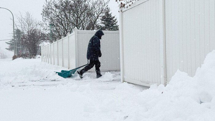 Un homme déneige son entrée à Sept-Îles.