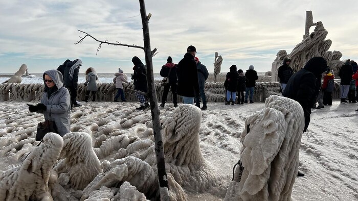 Des personnes visitent des sculptures gelées le long d'un lac.