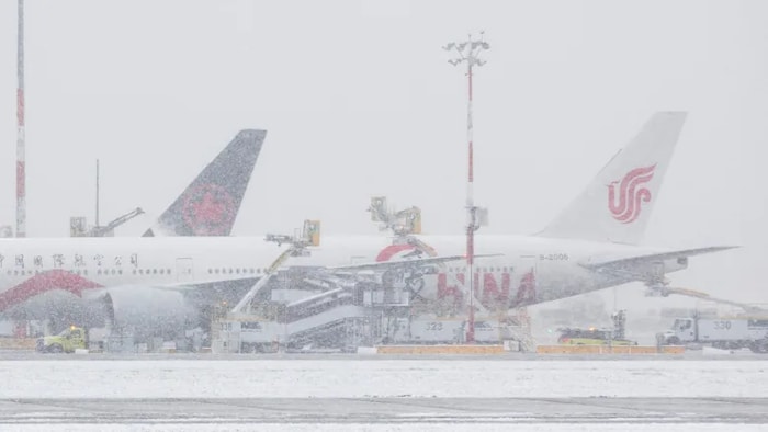طائرتان على مدرج مطار خلال عاصفة ثلجية.