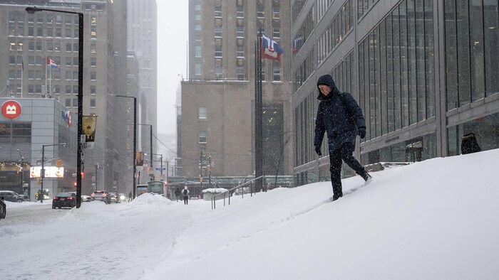 Un piéton descend des marches enneigées au centre-ville de Toronto, le 15 janvier 2026.