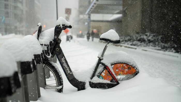 Un vélo en libre-service Bike Share stationnée dans sa borne est ensevelie sous la neige.