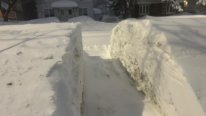 Un passage est déneigé entre une cour et le trottoir à Rouyn-Noranda.