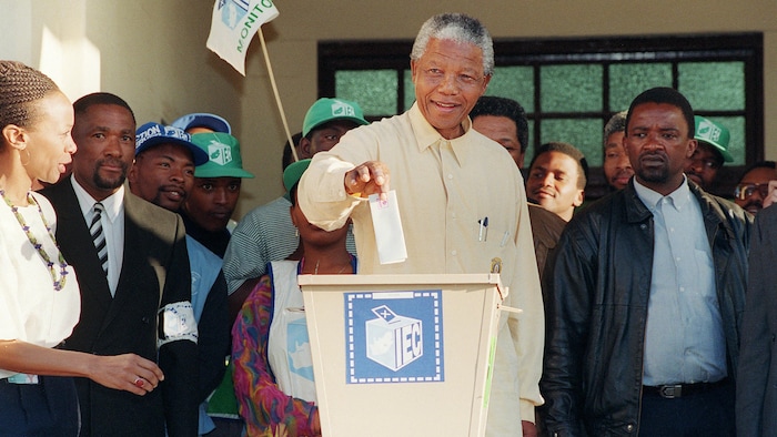 Nelson Mandela vote, entouré de personnes.