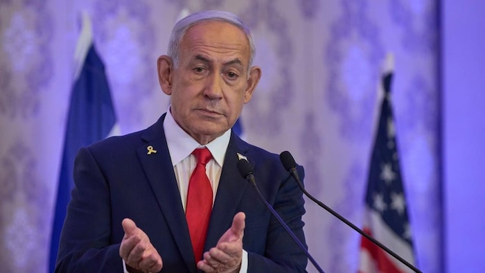 Le premier ministre israélien, Benyamin Nétanyahou, se tient derrière un lutrin et regarde droit devant. 