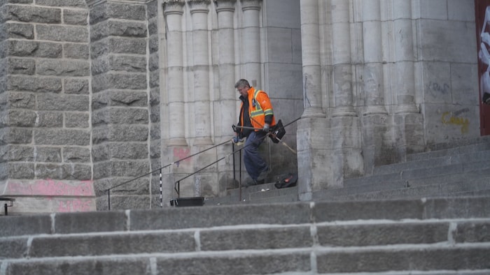 Un employé nettoie un parvis d'église. 