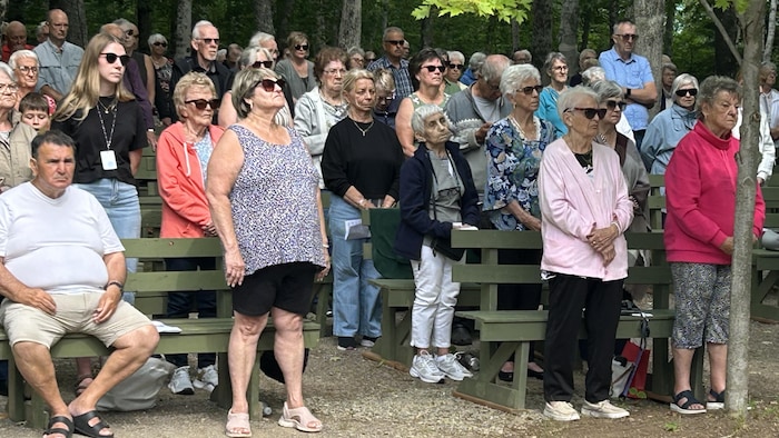 Une petite foule debout durant une célébration religieuse.