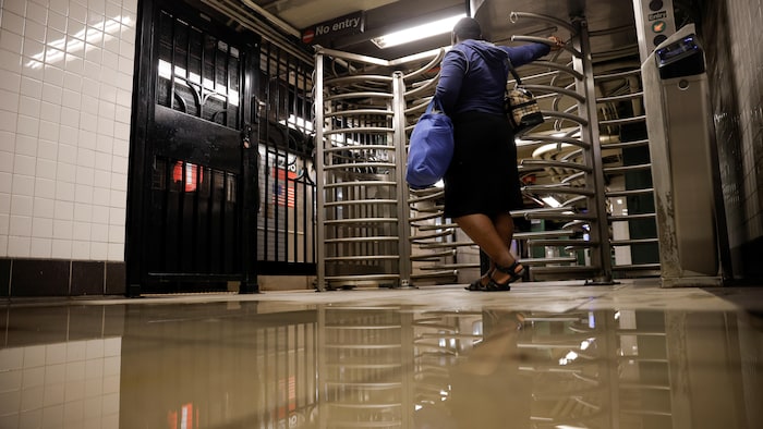 Une femme attend à l'entrée d'une station de métro alors que le plancher est presque totalement inondé.