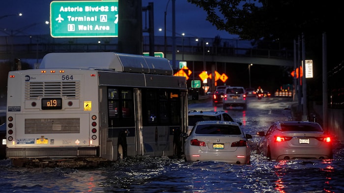 Un bus passe devant des voitures abandonnées sur une autoroute inondée dans le Queens, New York.