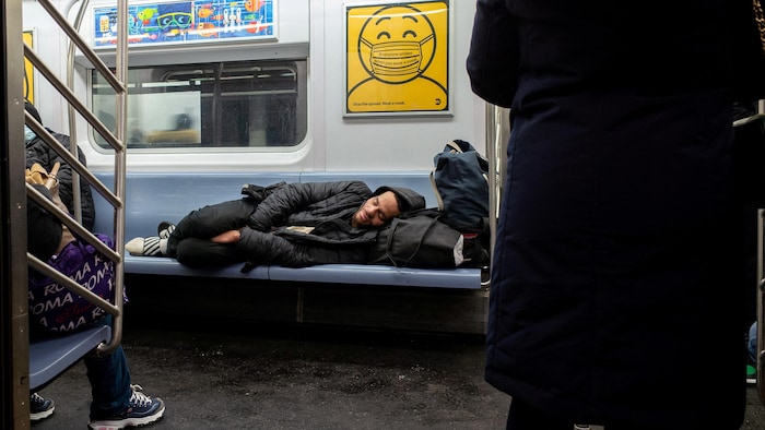 New York'ta metro koltuğunda yatan evsiz bir adam.