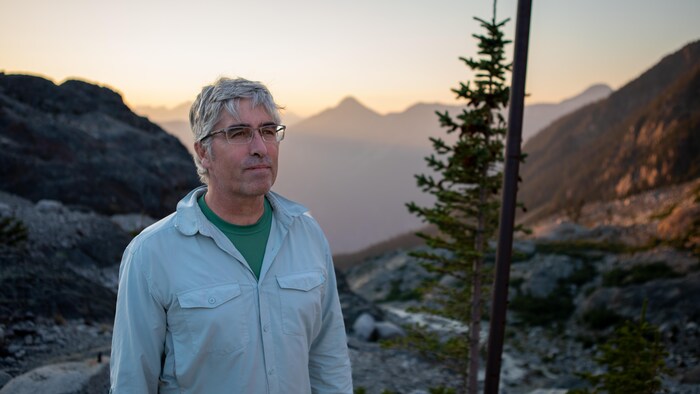 Portrait de Brian Menounos dans un paysage de montagnes.