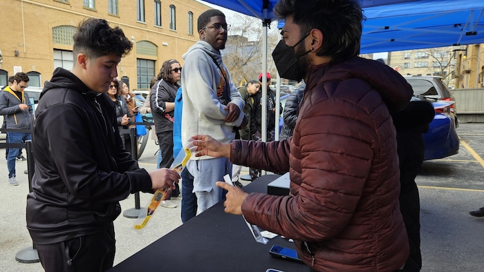 A man sells special eclipse glasses to a young man.