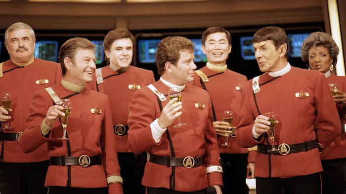Sept personnages de Star Trek célèbrent un verre à la main.