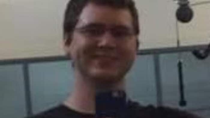 Une personne souriante portant un t-shirt noir.
