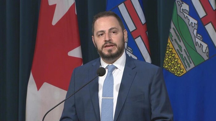 Le ministre de l'Éducation de l'Alberta, Demetrios Nicolaides, parle devant un pupitre.