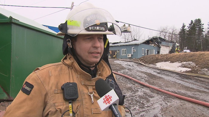 Nicolas Guay en entrevue devant le bâtiment endommagé par le feu.