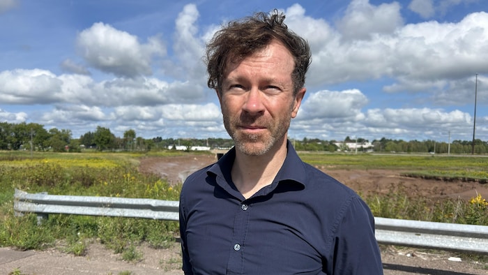 Un homme interviewé devant un terrain marécageux.