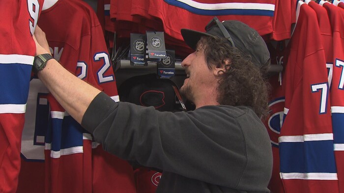 Il regarde les différents chandails sur les supports.