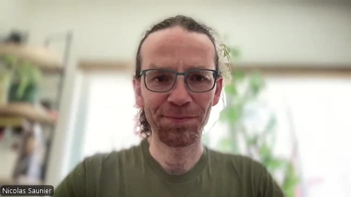 Portrait de Nicolas Saunier qui porte des lunettes de vue, un t-shirt, avec les cheveux attachés en arrière.