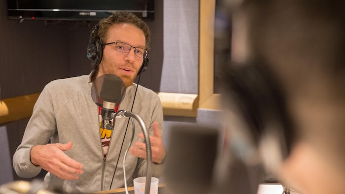 Une photo du professeur Nicolas Saunier en train de parler au micro dans un studio de radio.