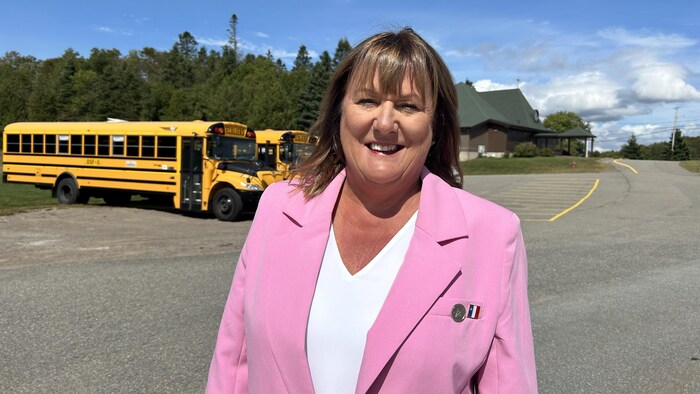 Nicole Arseneau-Sluyter dehors, devant des autobus scolaires.