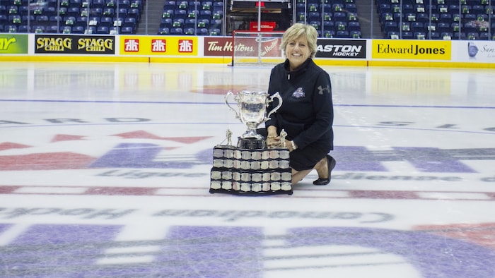 Nicole Bouchard pose au centre de la glace avec la coupe Memorial. 