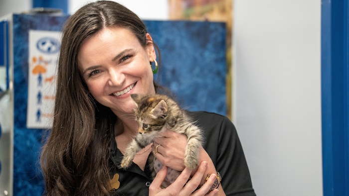Nicole Bryce souriant à la caméra, avec un petit chaton dans les bras.