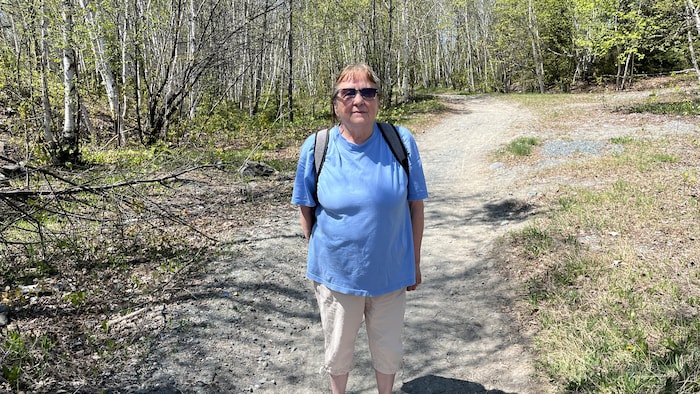 Une femme debout dans un sentier de forêt.