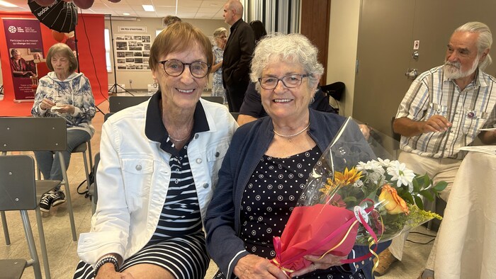 Nicole Pineau et Françoise St-Laurent prennent la pose. Françoise tient des fleurs dans ses bras.