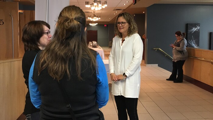 Une femme discute avec des participantes lors d'un colloque.