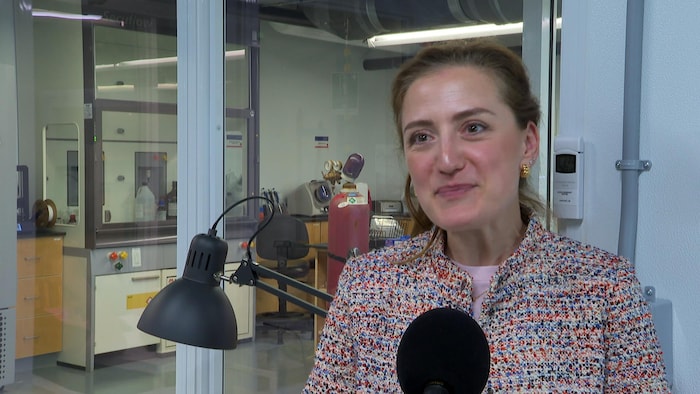 Une femme interviewée devant un laboratoire.