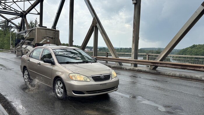 Un véhicule roule dans un trou d'eau sur le pont de Monseigneur-Albert-Gravel.